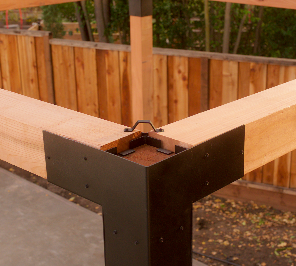 Wooden beam with metal bracket against a wooden fence background