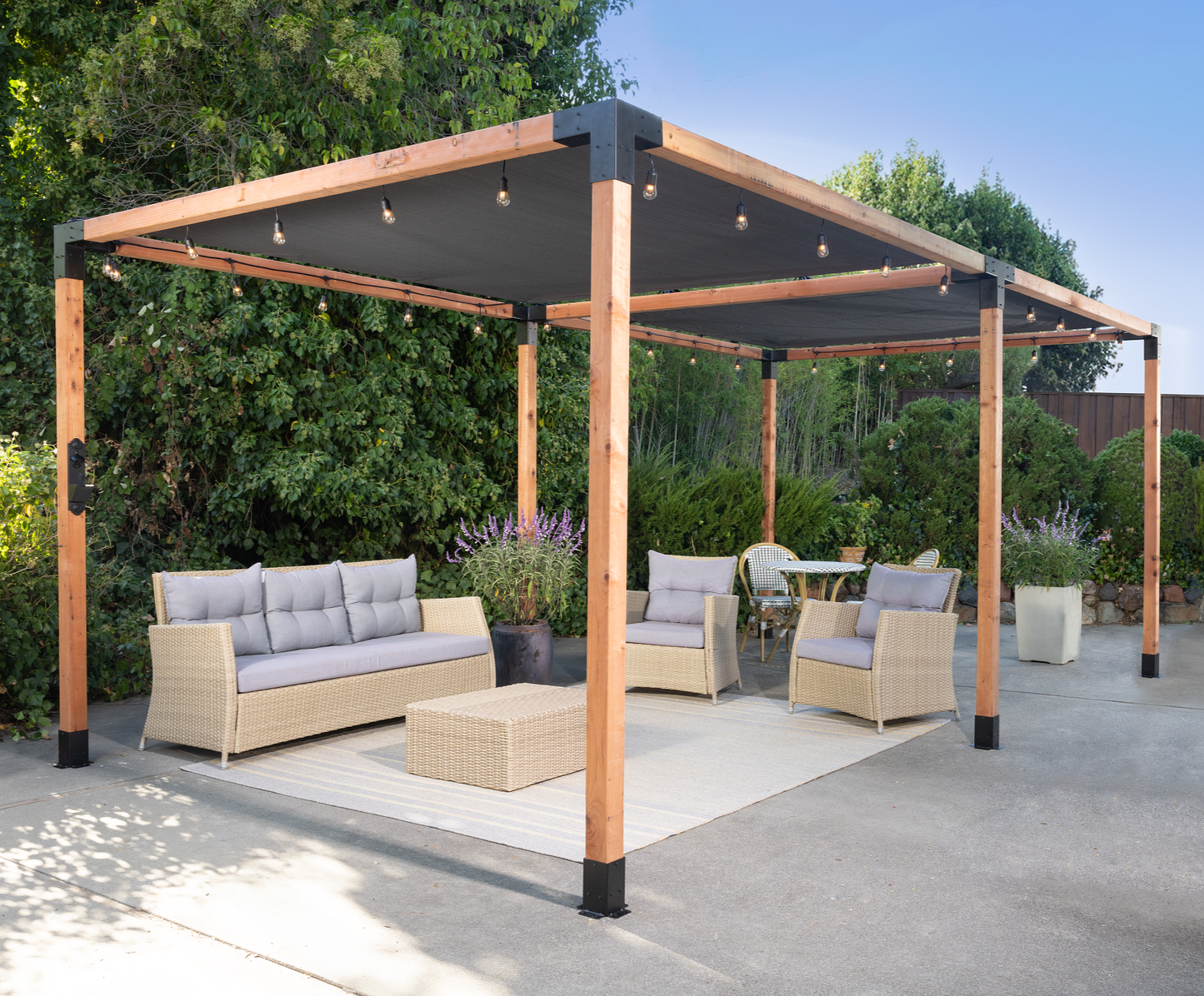 Outdoor patio with pergola, furniture, and plants on a sunny day.