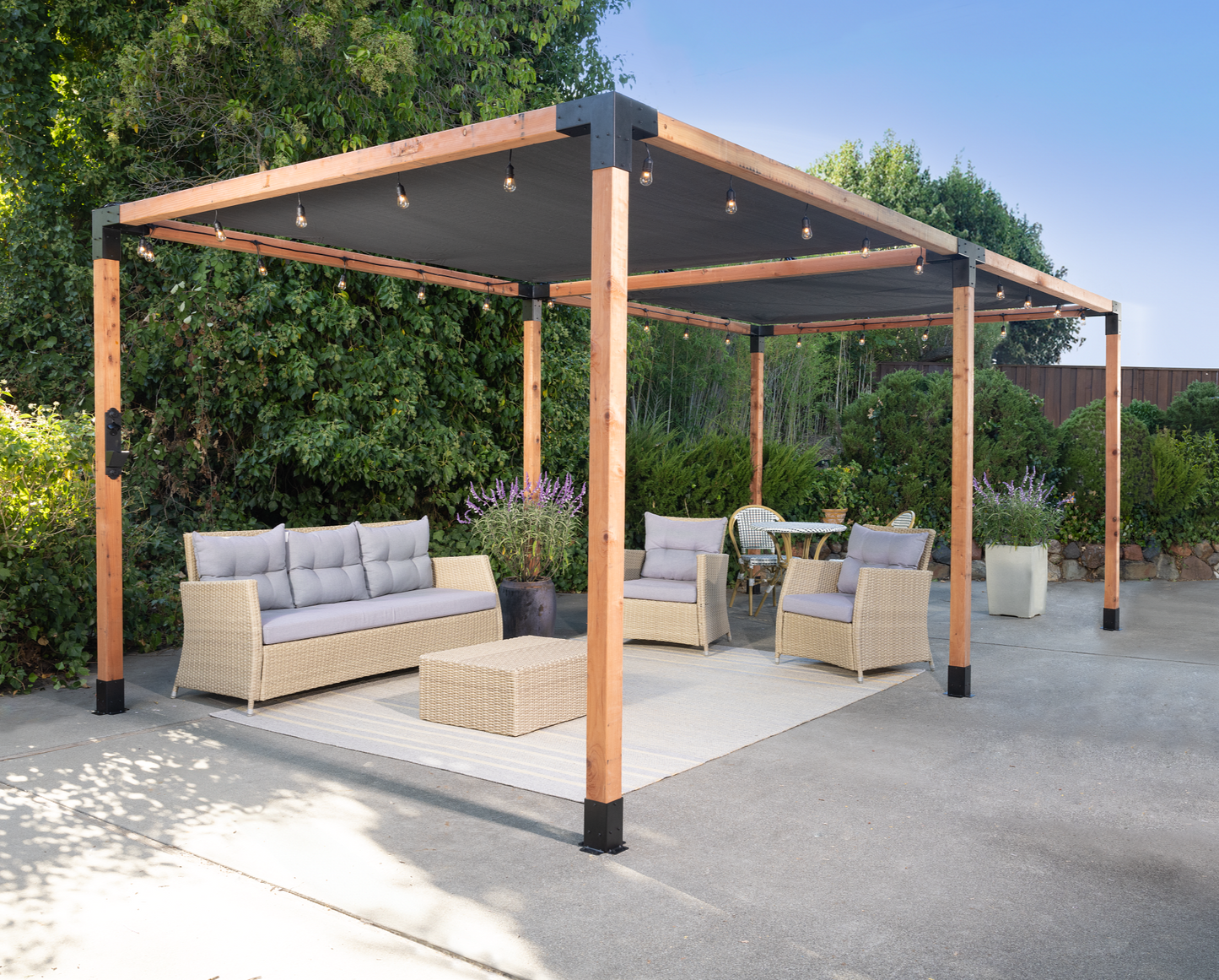 Outdoor patio with pergola, furniture, and plants on a sunny day.