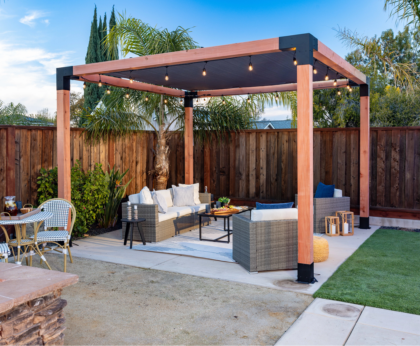 Outdoor patio with pergola, seating area, and fire pit in a backyard setting.