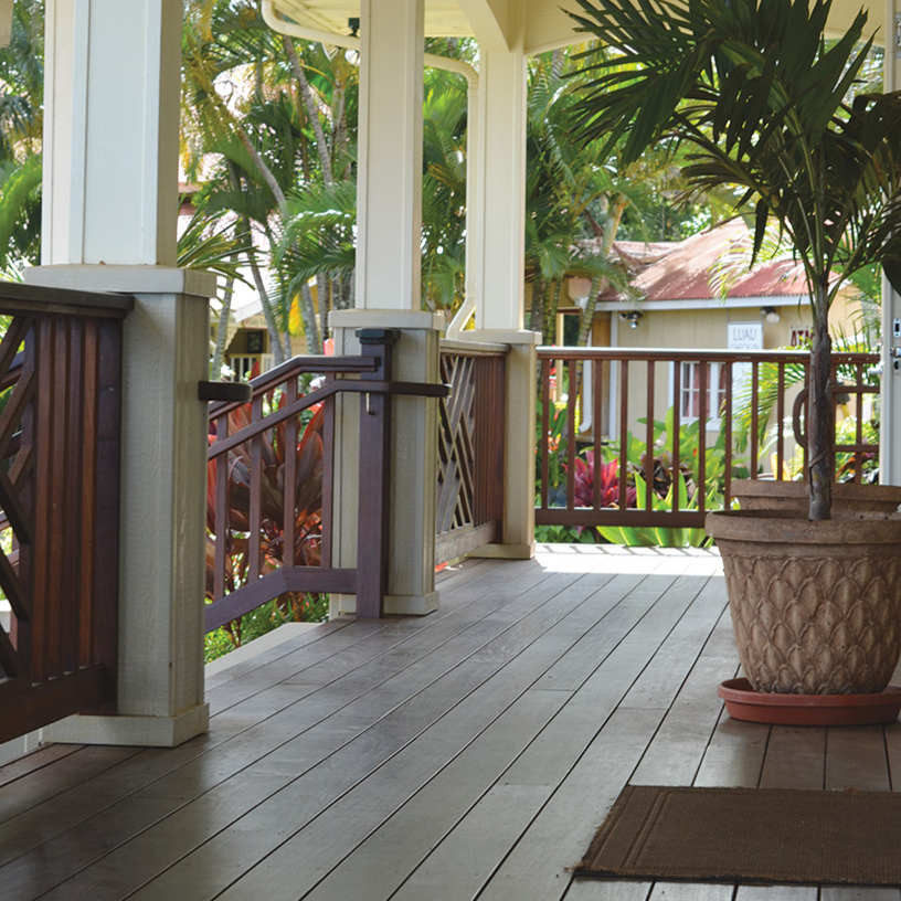 Porch with wooden floor, white columns, and potted plant