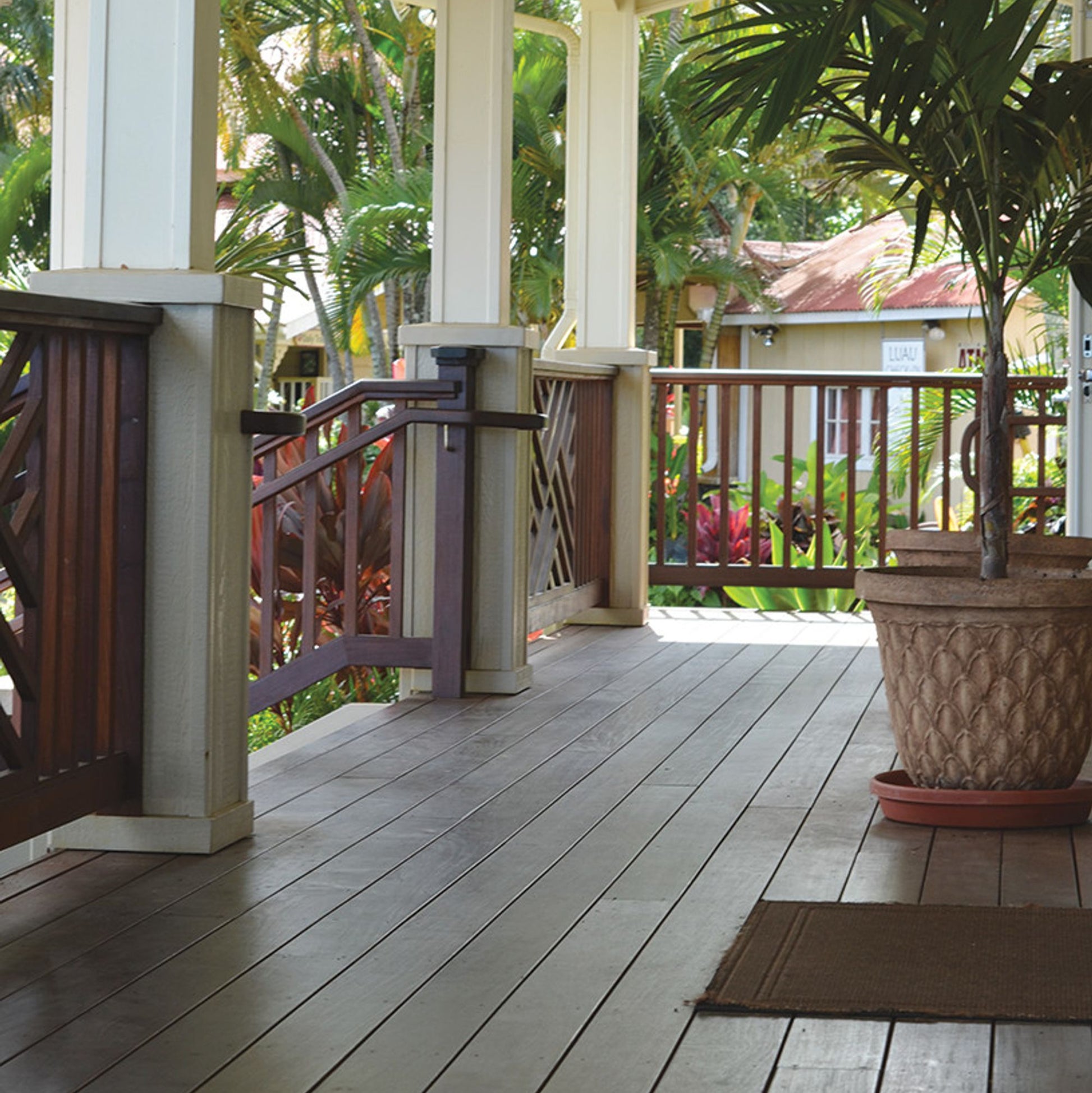 Wooden porch with a railing, potted plant, and view of greenery