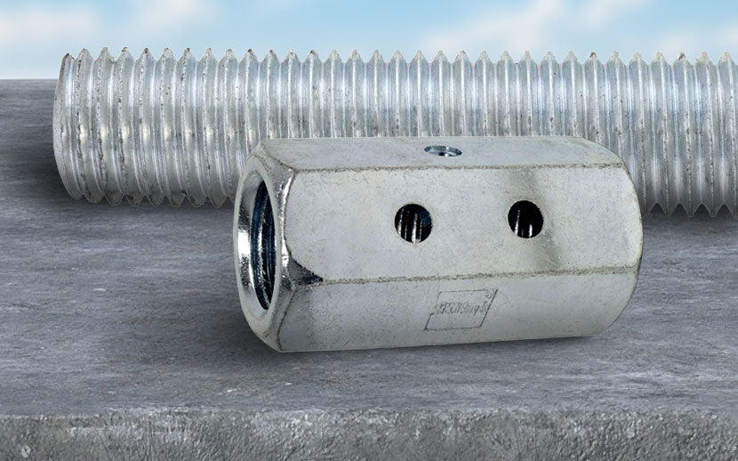 Coupler nut on a concrete surface with threaded rod in the background