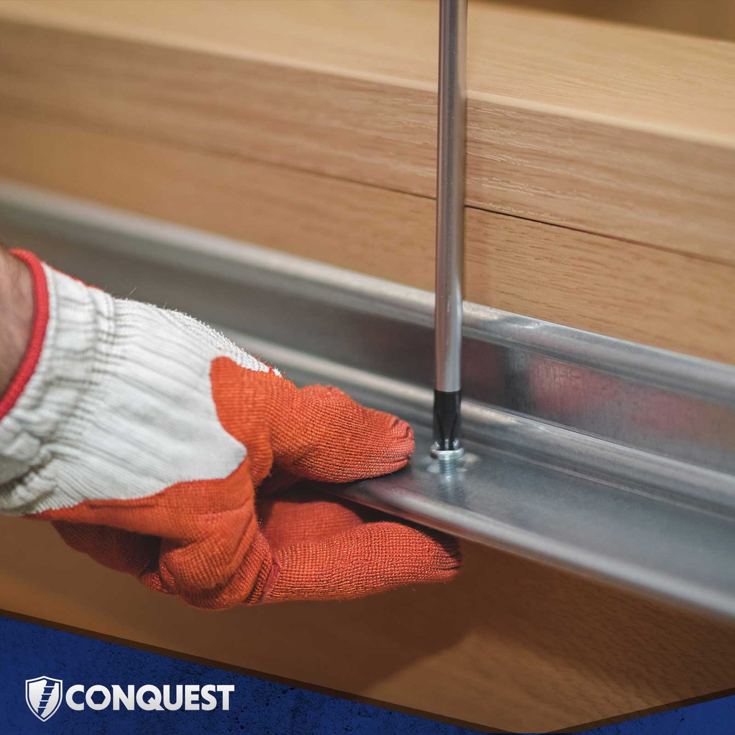 Hand wearing an orange glove using a tool to install machine screws