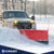 White truck with a red snow plow clearing snow in a winter landscape