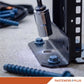 Close-up of a black metal mounting bracket being secured with a socket wrench and blue concrete anchor screws