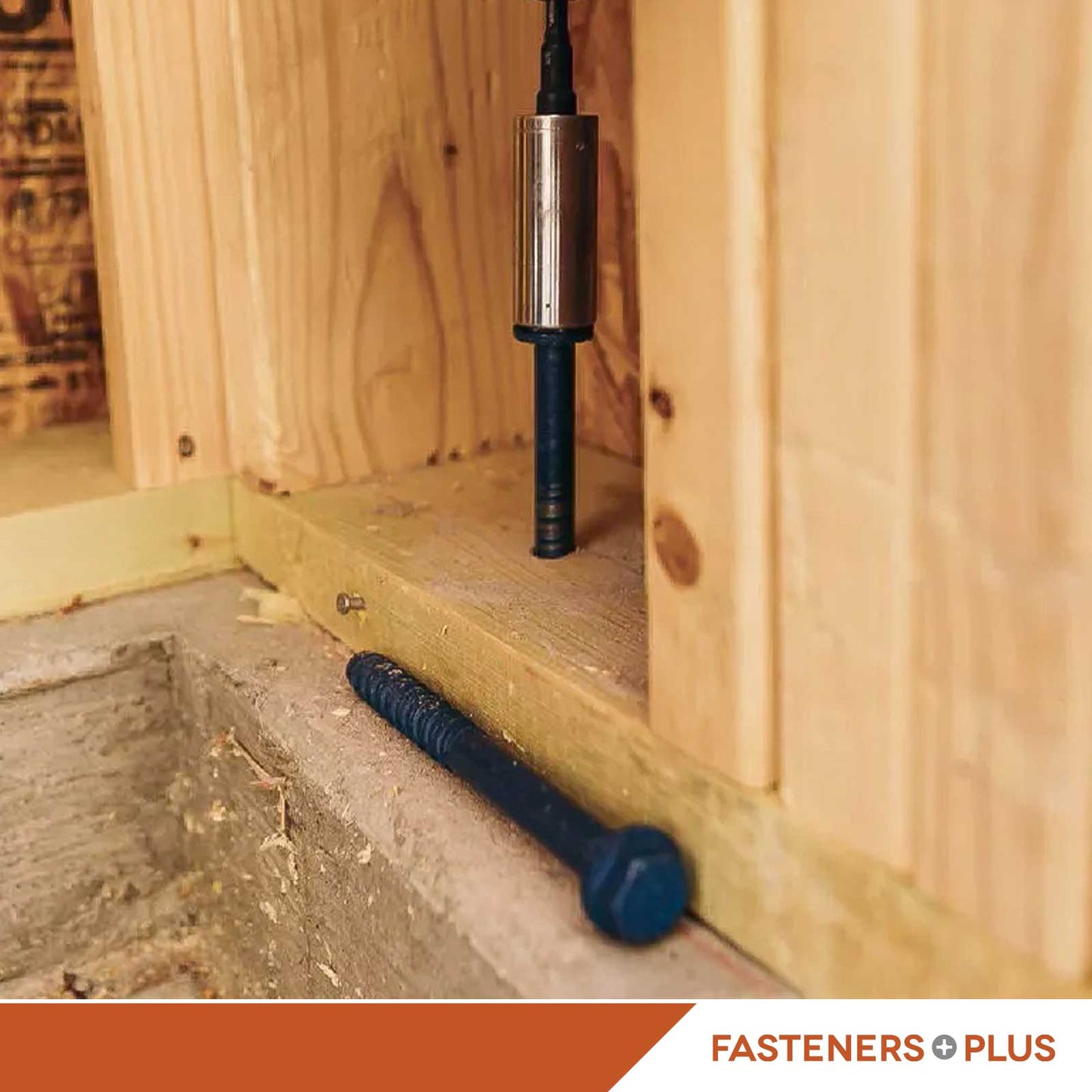Close-up of a blue concrete screw anchor installed in a wooden frame and concrete base
