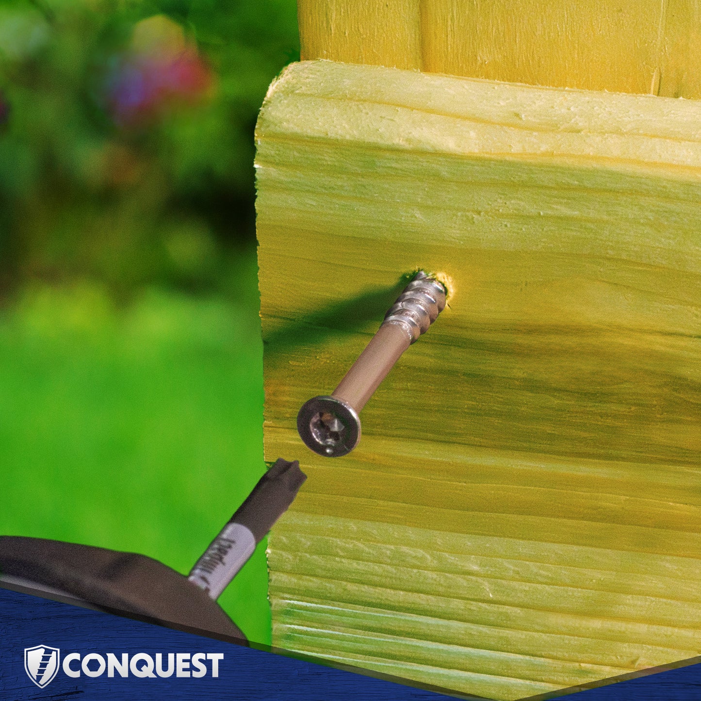 Screw being driven into a yellow wooden surface with 'Conquest' branding visible.