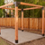 Completed Simpson Sage DIY Pergola structure on a concrete slab with a wooden fence and trees in the background