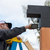 Person on a ladder showing how to drill Simpson Sage Corner Connector to a Wood Post