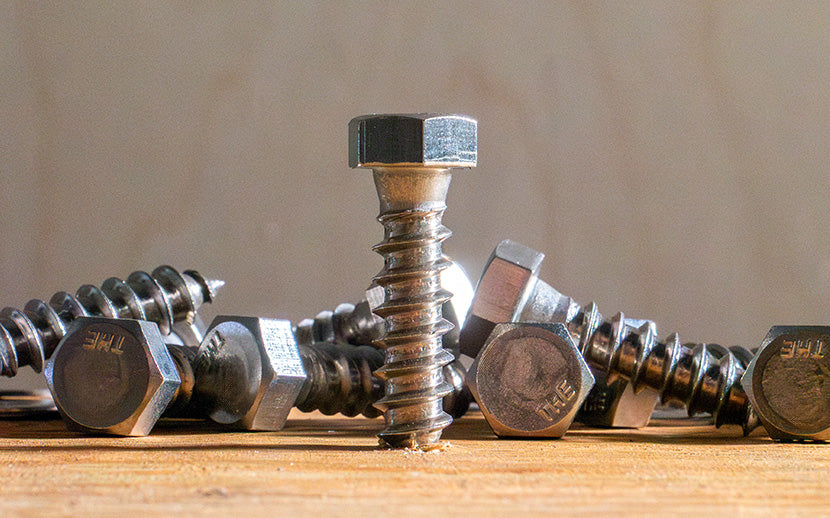 A lag bolt screwed into wood, surrounded by other lag bolts