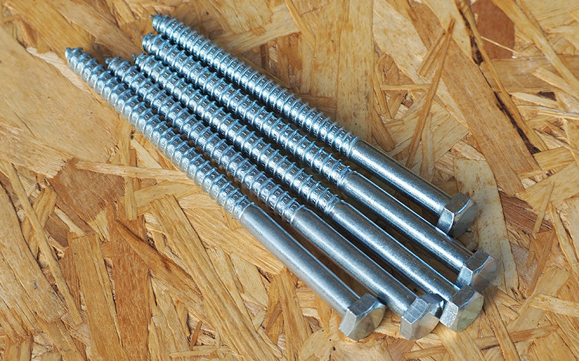 An assortment of lag bolts laying on OSB board