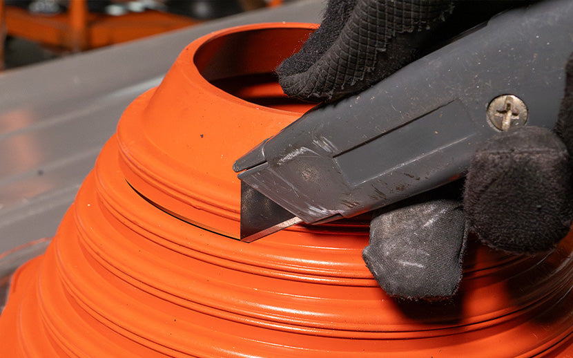 Using a utility knife to cut a rubber roof boot to size