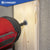 Red drill being used on a wooden block with concrete wall background, featuring the Conquest brand.