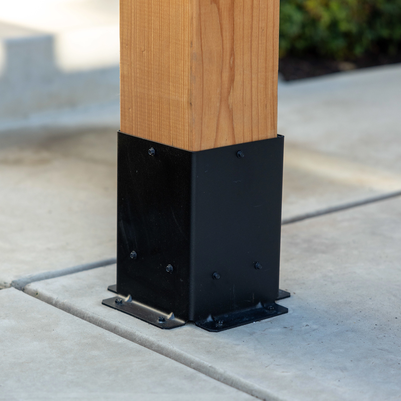 Black Decorative Post Base installed on Wooden Post on concrete floor