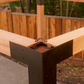 Wooden beam with metal bracket against a wooden fence background