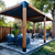 Outdoor patio with wooden pergola, chairs, and table in a backyard setting.