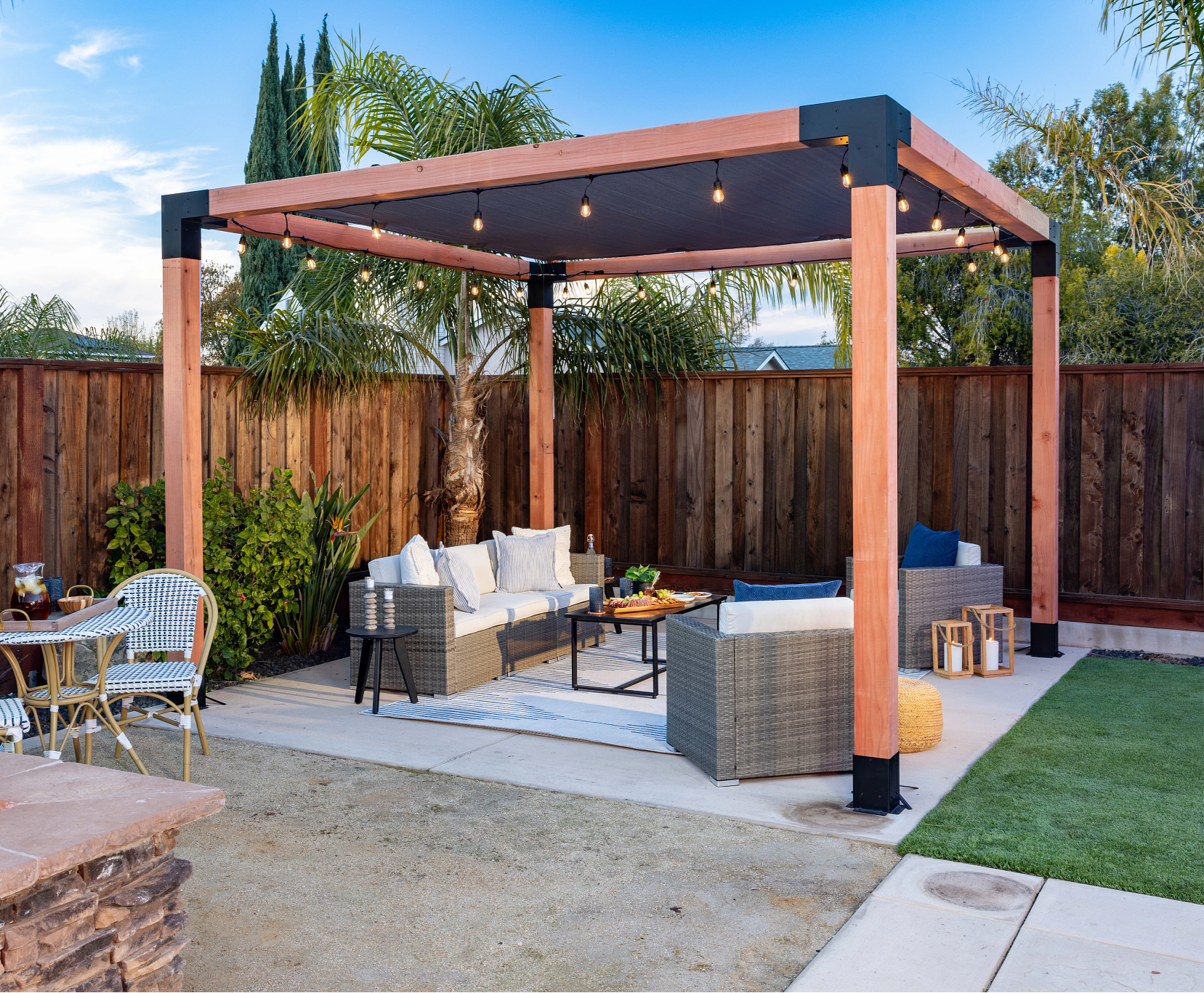 Outdoor patio with pergola, seating area, and fire pit in a backyard setting.