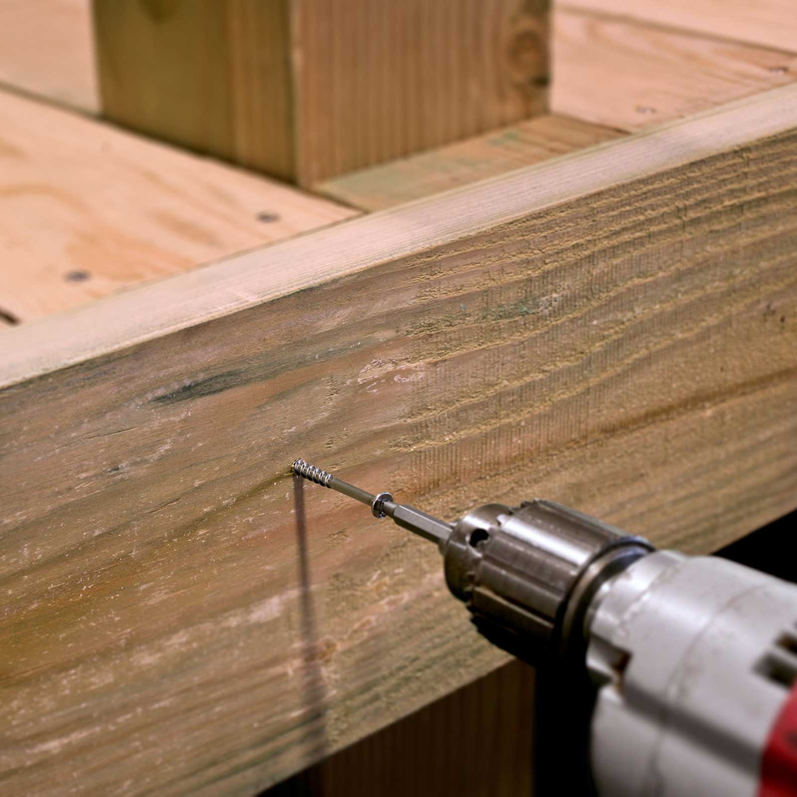 screw being installed with a drill into a wooden deck