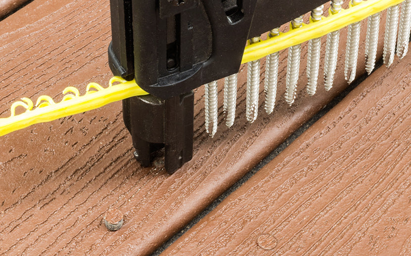 Close-up of a nail gun with screws on a composite deck