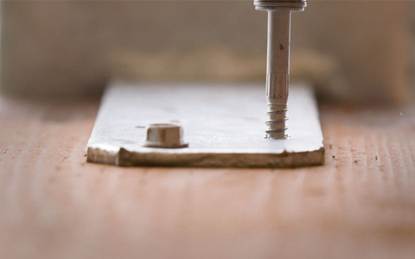 Screw being driven into a deck tie on a wooden surface