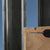 Wooden board with a screw and drill bit against a metal frame and blue sky background