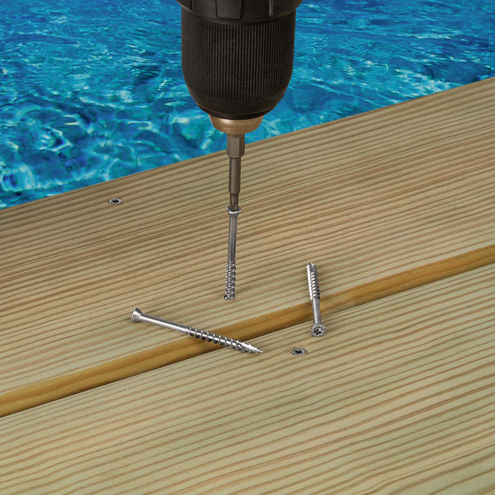 Drill bit being used to drive screws into wooden planks with a pool in the background