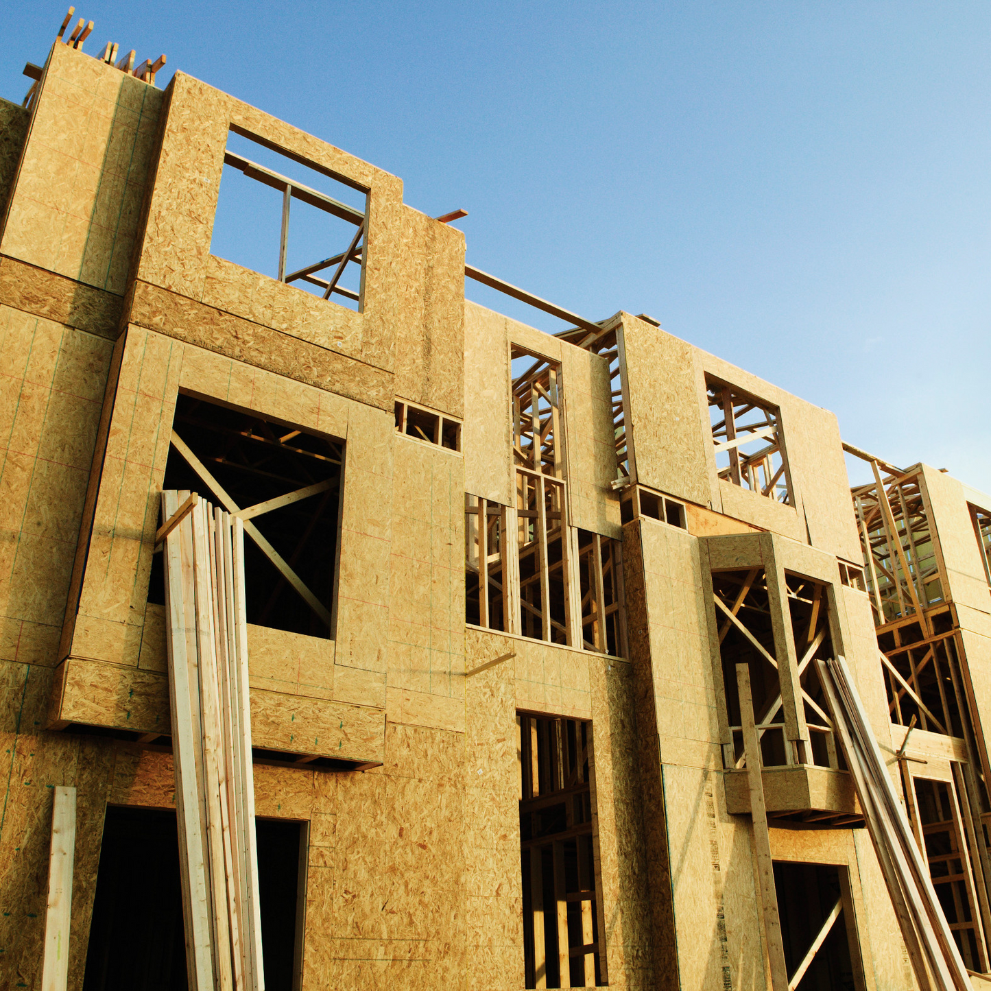 Building under construction with wooden frames against a clear blue sky