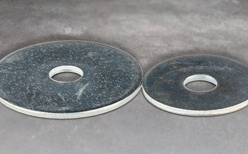 Two gray fender washers on a concrete surface
