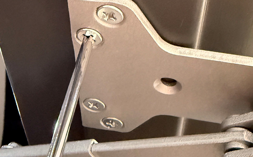 Metal bracket with machine screws and a tool being used on it