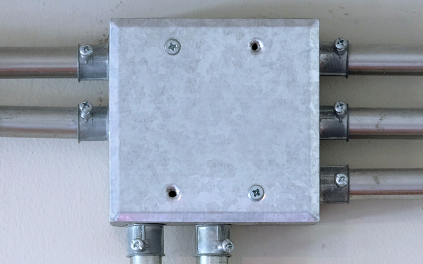 Metal box with pipes attached on a plain background and machine screws