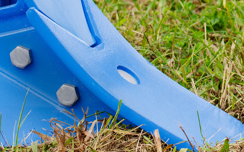 Close-up of a blue metal plow equipment with plow bolts on grass