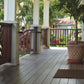 Wooden porch with a railing, potted plant, and view of greenery