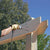 Person using a drill on a wooden structure with trees and blue sky in the background