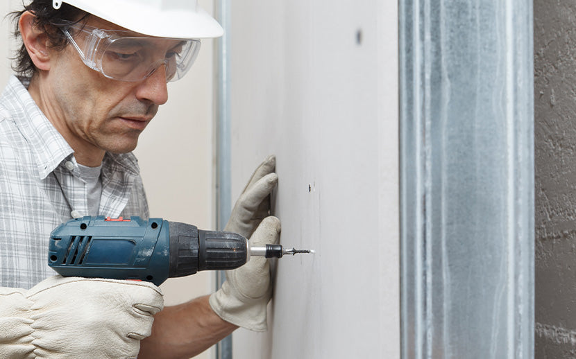 Person using a drill on drywall