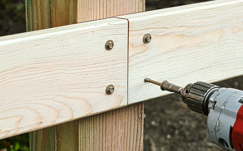 Drilling structural screws into wooden planks with a power drill.