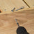 Screws on a wooden surface with a drill drilling a screw