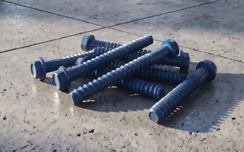 A pile of blue concrete screw anchors with hex heads resting on a concrete surface.